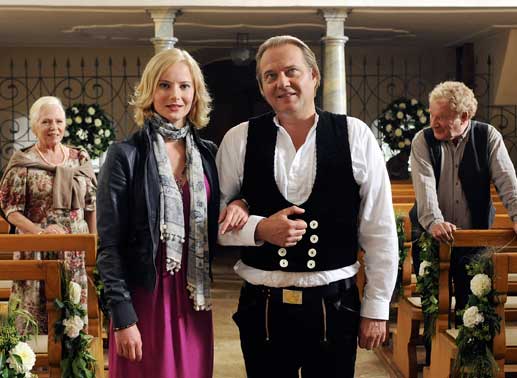 Gerd (Jan-Gregor Kremp, 2.v.re.) mit seiner Tochter Lisette (Teresa Wei&szlig;bach) bei den Proben f&uuml;r die Hochzeitszeremonie. Sein Vater Heinrich (Michael Hanemann) und dessen Geliebte Ilse (Angelika Bender) sind ger&uuml;hrt. Bild: Sender