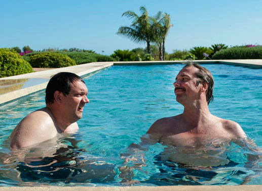 Geschäftsmeeting im Pool: Lorenz (Charly Hübner, l.) und Alexander (Michael Maertens, r.) genie&szlig;en den neuen Luxus auf Mallorca. Bild: Sender / Max Kohr