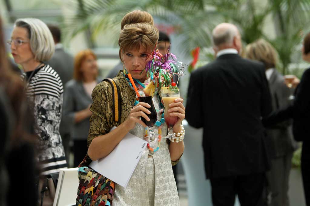 Fanny (Anke Engelke) versucht, sich auf der Konzern-Party mit gleich zwei Begr&uuml;&szlig;ungscocktails vor Gretchen und ihrem Mann, Minister Heinze, zu verstecken. Bild: Sender / Joerg Landsberg / Brainpool