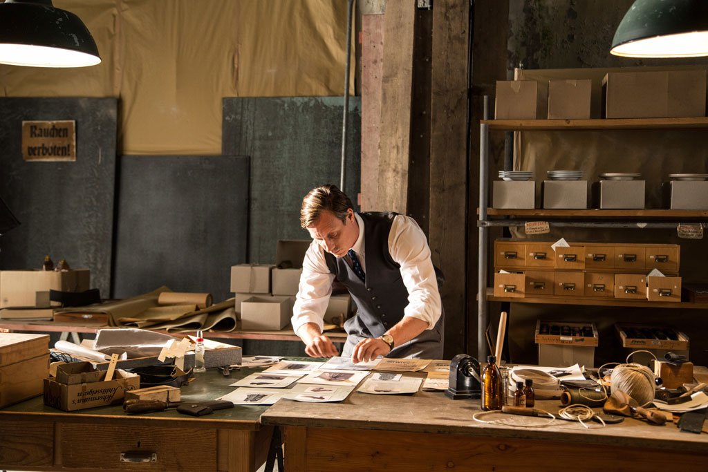 Firmenchef Werner Otto (Patrick Kalupa) stellt in Handarbeit die Seiten seines aktuellen Versandkatalogs zusammen. Bild: Sender / Oliver Halmburger 